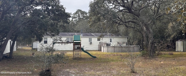 back of house with a shed and a playground