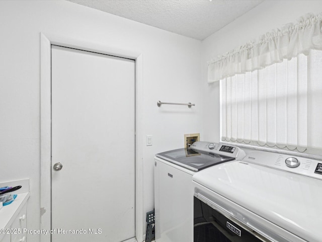 clothes washing area featuring washing machine and clothes dryer and a textured ceiling