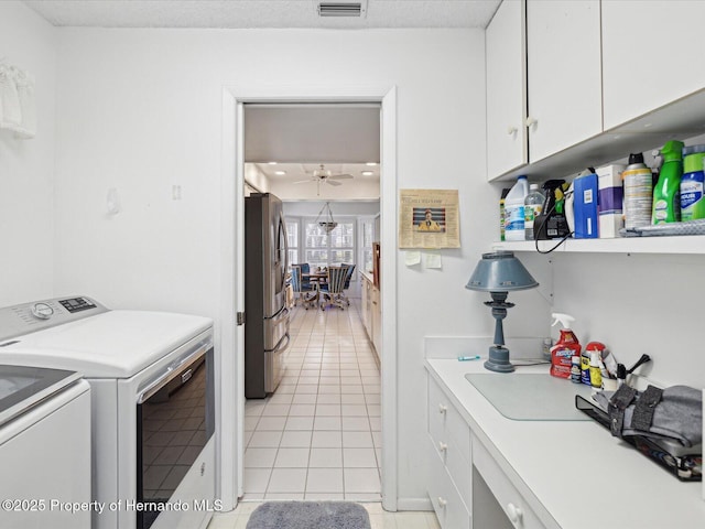 laundry area featuring light tile patterned floors, cabinets, washing machine and clothes dryer, and ceiling fan