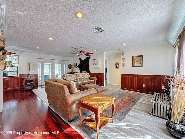 living room featuring a textured ceiling, crown molding, hardwood / wood-style floors, and french doors