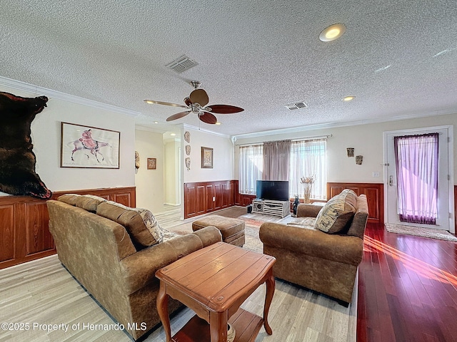 living room with a textured ceiling, ceiling fan, crown molding, and light hardwood / wood-style floors