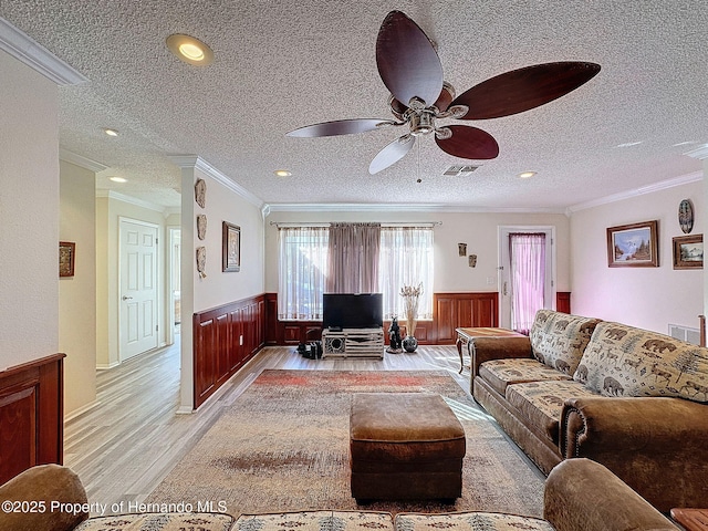 living room with ceiling fan, crown molding, a textured ceiling, and light hardwood / wood-style floors