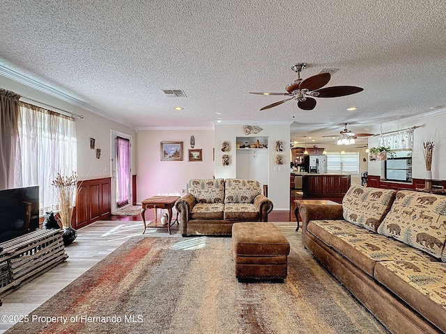 living room with ceiling fan, crown molding, a textured ceiling, and light hardwood / wood-style flooring