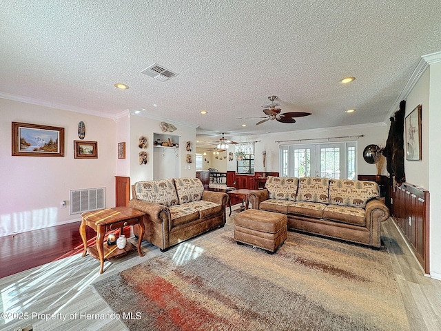 living room featuring ceiling fan, light hardwood / wood-style floors, crown molding, radiator, and a textured ceiling