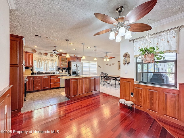 kitchen featuring a kitchen island, a kitchen breakfast bar, hanging light fixtures, stainless steel fridge with ice dispenser, and crown molding