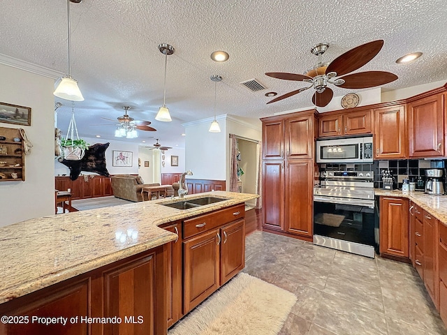 kitchen with pendant lighting, sink, crown molding, stainless steel appliances, and light stone counters