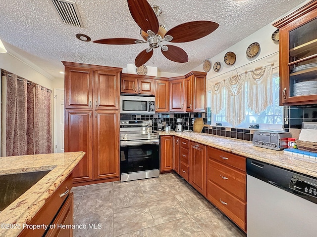 kitchen featuring ceiling fan, decorative backsplash, light stone countertops, stainless steel appliances, and a textured ceiling