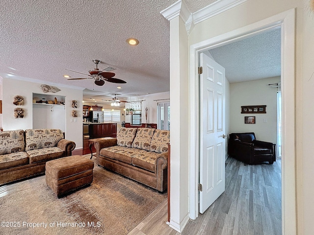 living room with a textured ceiling, ceiling fan, crown molding, and hardwood / wood-style floors