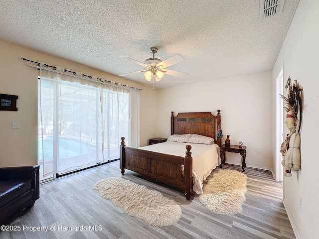 bedroom with ceiling fan, access to exterior, a textured ceiling, and hardwood / wood-style floors