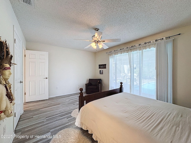 bedroom with ceiling fan, dark hardwood / wood-style floors, and a textured ceiling