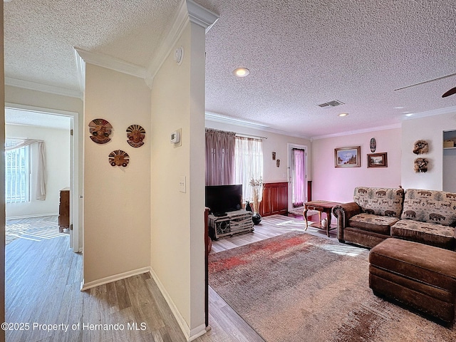 living room featuring light wood-type flooring, a textured ceiling, crown molding, and ceiling fan