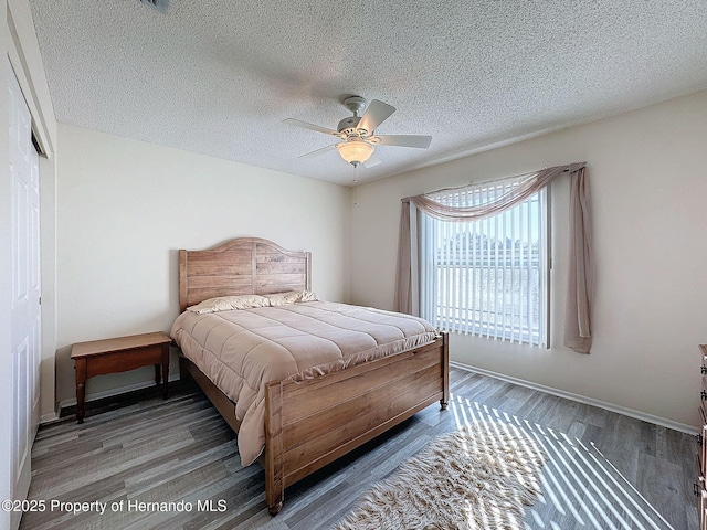 bedroom with ceiling fan, dark hardwood / wood-style flooring, and a textured ceiling