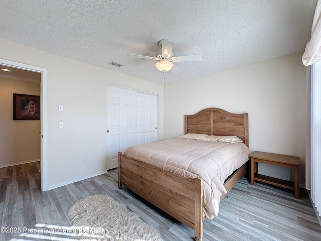 bedroom with ceiling fan, a closet, a textured ceiling, and hardwood / wood-style flooring