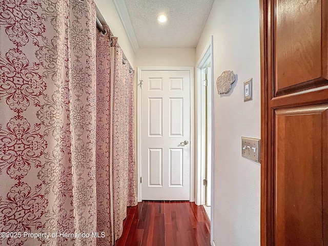 corridor with a textured ceiling, dark hardwood / wood-style flooring, and ornamental molding