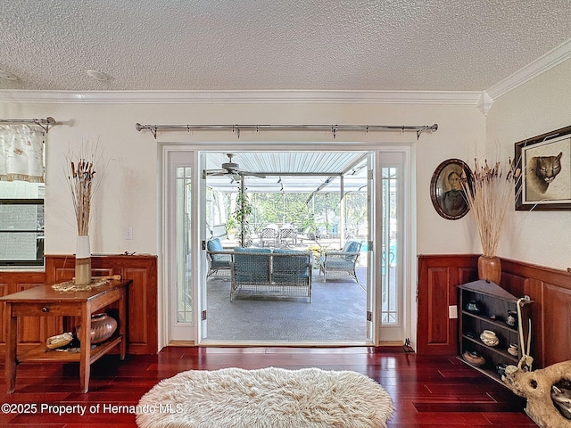 doorway to outside featuring a textured ceiling, dark hardwood / wood-style floors, and crown molding