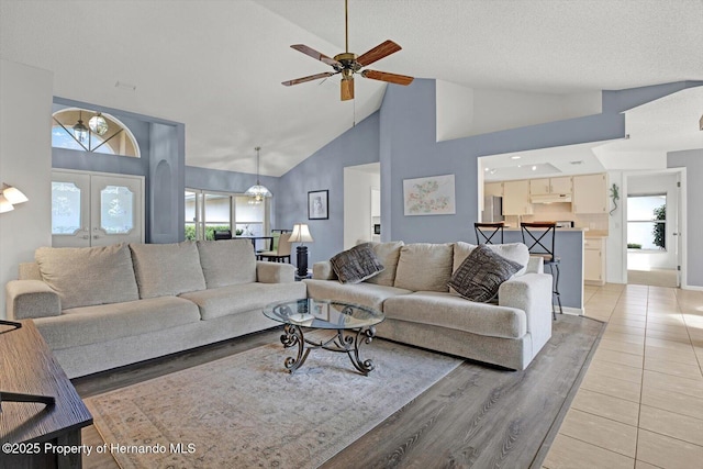 living room with a textured ceiling, a wealth of natural light, high vaulted ceiling, and ceiling fan