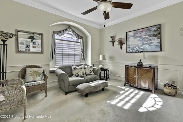 living area featuring ceiling fan, light colored carpet, and crown molding