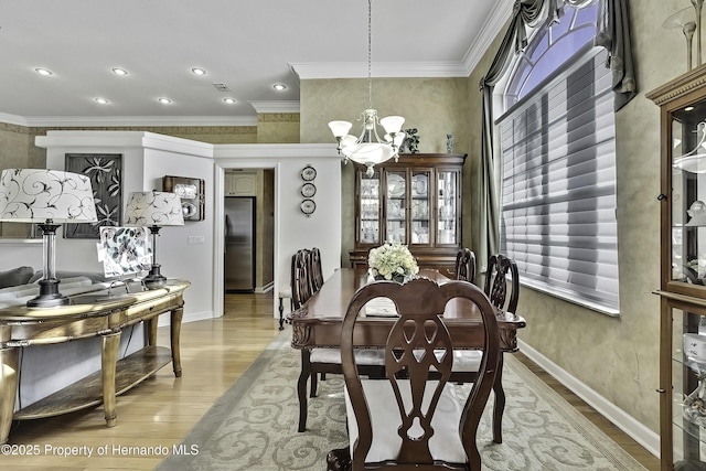 dining room with ornamental molding, an inviting chandelier, and light wood-type flooring