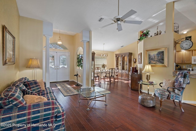 living room featuring decorative columns, dark hardwood / wood-style floors, ceiling fan with notable chandelier, vaulted ceiling, and french doors