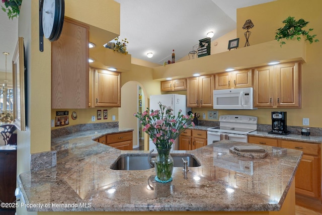 kitchen with light stone counters, white appliances, vaulted ceiling, and kitchen peninsula