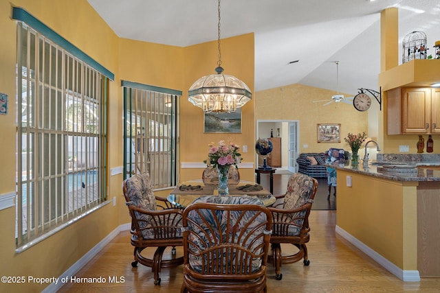 dining area with lofted ceiling, sink, ceiling fan with notable chandelier, and light wood-type flooring