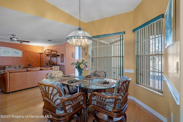 dining space with ceiling fan with notable chandelier and light hardwood / wood-style floors