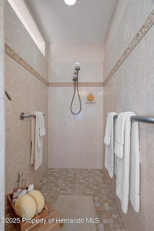 bathroom featuring tile walls and a tile shower