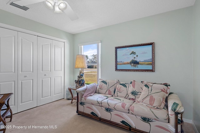 carpeted living room with ceiling fan and a textured ceiling