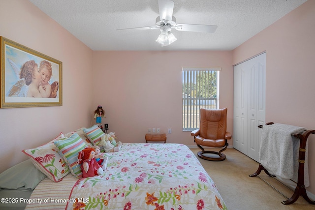 carpeted bedroom with ceiling fan, a closet, and a textured ceiling