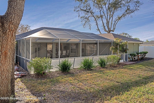 rear view of house with a yard and a lanai