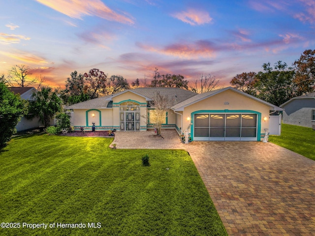 ranch-style house with a garage and a lawn