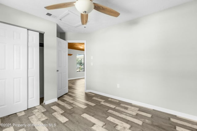 unfurnished bedroom with ceiling fan, dark wood-type flooring, and a closet