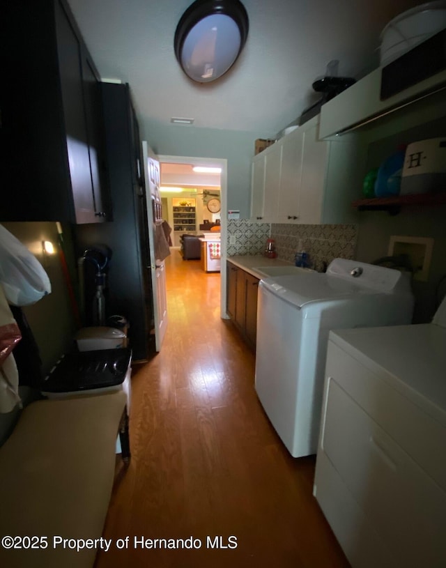 clothes washing area with cabinets, sink, light hardwood / wood-style floors, and washer and dryer