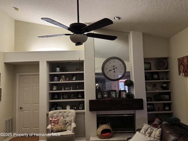 living room with built in shelves, lofted ceiling, and a textured ceiling