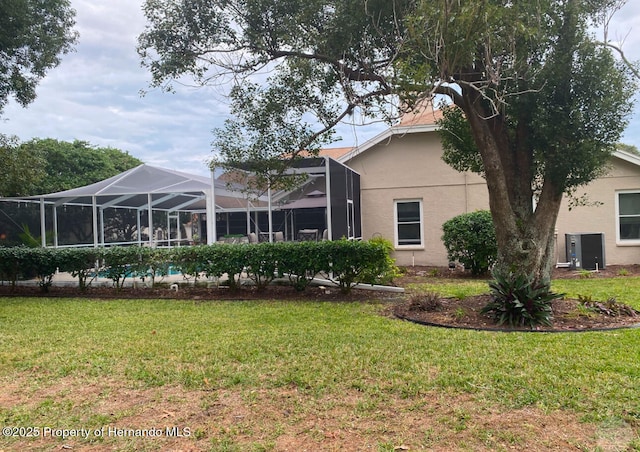 back of house featuring a lanai and a yard