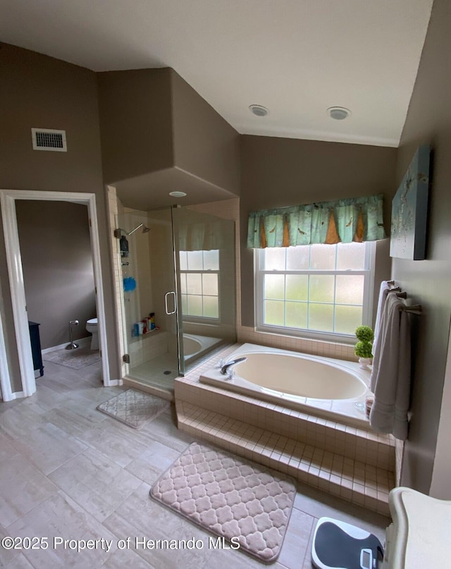 bathroom with tile patterned flooring, shower with separate bathtub, vaulted ceiling, and toilet