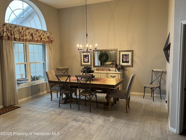 dining space featuring a chandelier, a high ceiling, wood finish floors, and baseboards