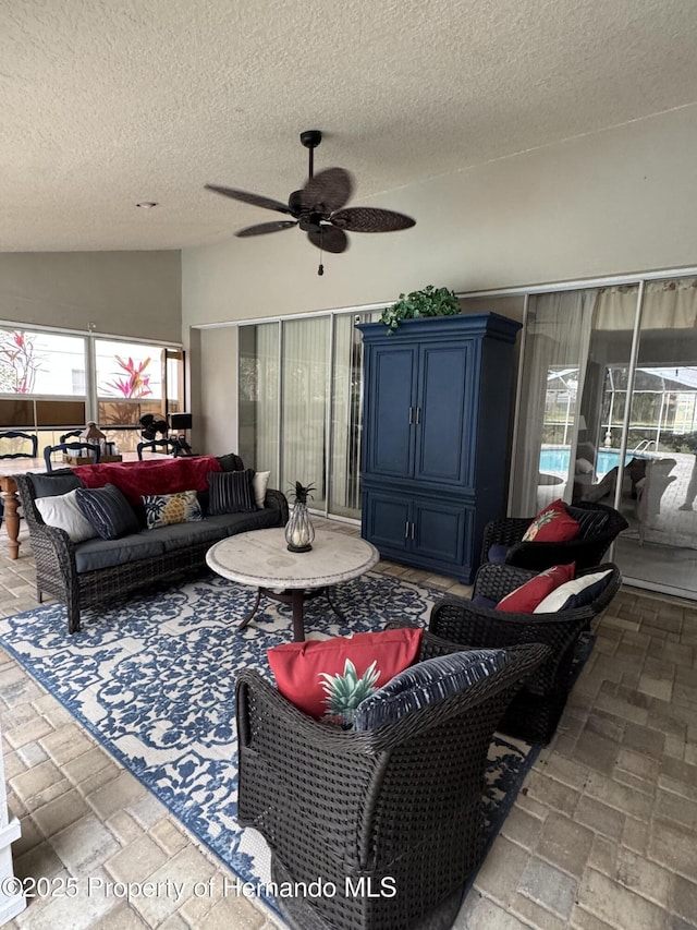 living room with ceiling fan, lofted ceiling, and a textured ceiling