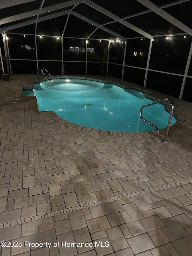 pool at night featuring a lanai and a patio area