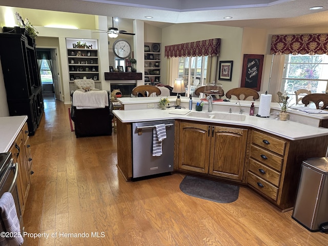 kitchen with light wood-style flooring, a fireplace, a sink, open floor plan, and dishwasher