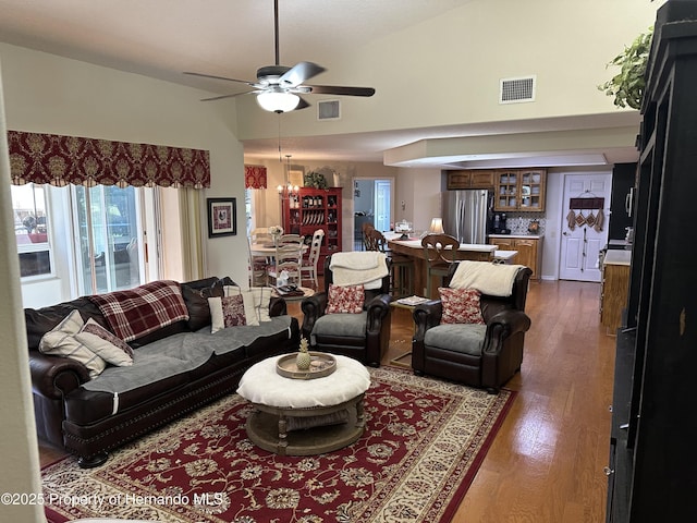 living area with high vaulted ceiling, visible vents, and wood finished floors