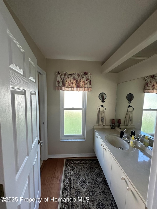 bathroom featuring vanity, baseboards, and wood finished floors