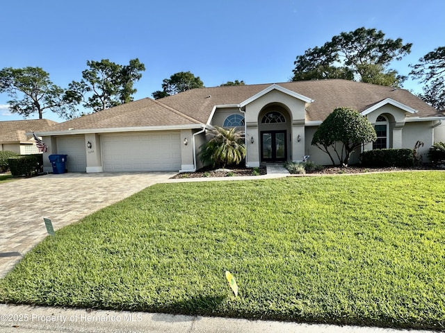 single story home featuring french doors, decorative driveway, a front lawn, and stucco siding