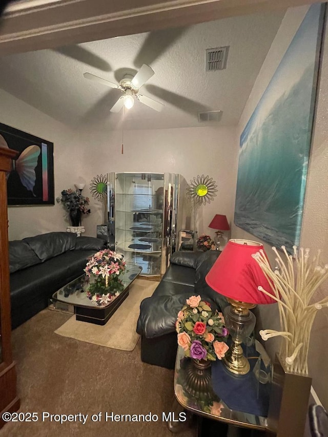 carpeted living room with ceiling fan and a textured ceiling