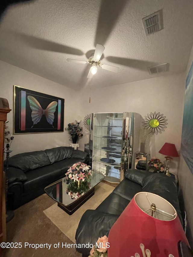 living room with carpet floors, a textured ceiling, and ceiling fan