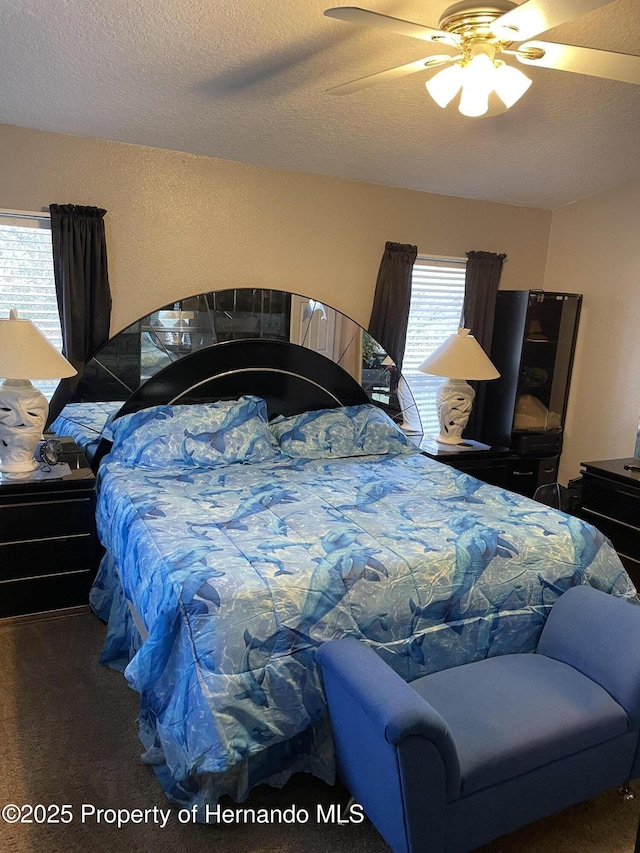 carpeted bedroom featuring ceiling fan, multiple windows, and a textured ceiling