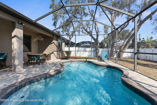 view of swimming pool featuring a patio, glass enclosure, a fenced backyard, and a fenced in pool