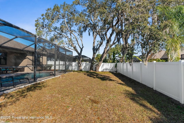 view of yard with a patio, a fenced backyard, a fenced in pool, and a lanai