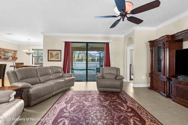 living room featuring light tile patterned floors, baseboards, arched walkways, crown molding, and ceiling fan with notable chandelier