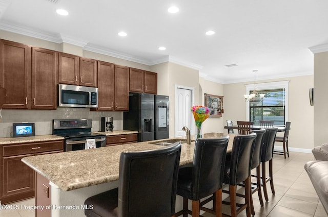 kitchen featuring a kitchen island with sink, appliances with stainless steel finishes, tasteful backsplash, a kitchen bar, and crown molding